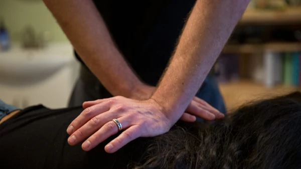 Close-up of a chiropractic adjustment being performed on the back using manual pressure.