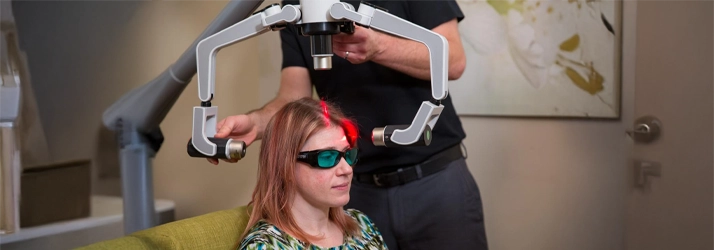 A female patient undergoes a laser therapy procedure with a specialized overhead