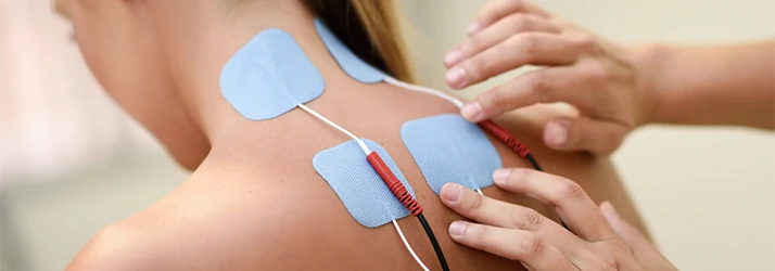Electrode pads applied to the upper back during a therapeutic electrical stimulation treatment.
